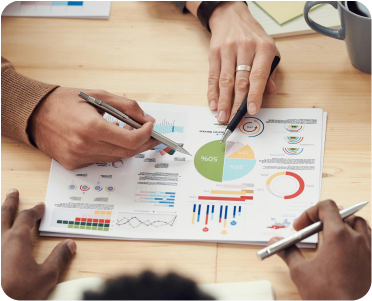 Profissionais discutindo gráficos e dados financeiros em uma mesa, representando análise e otimização de campanhas para consultorias financeiras.